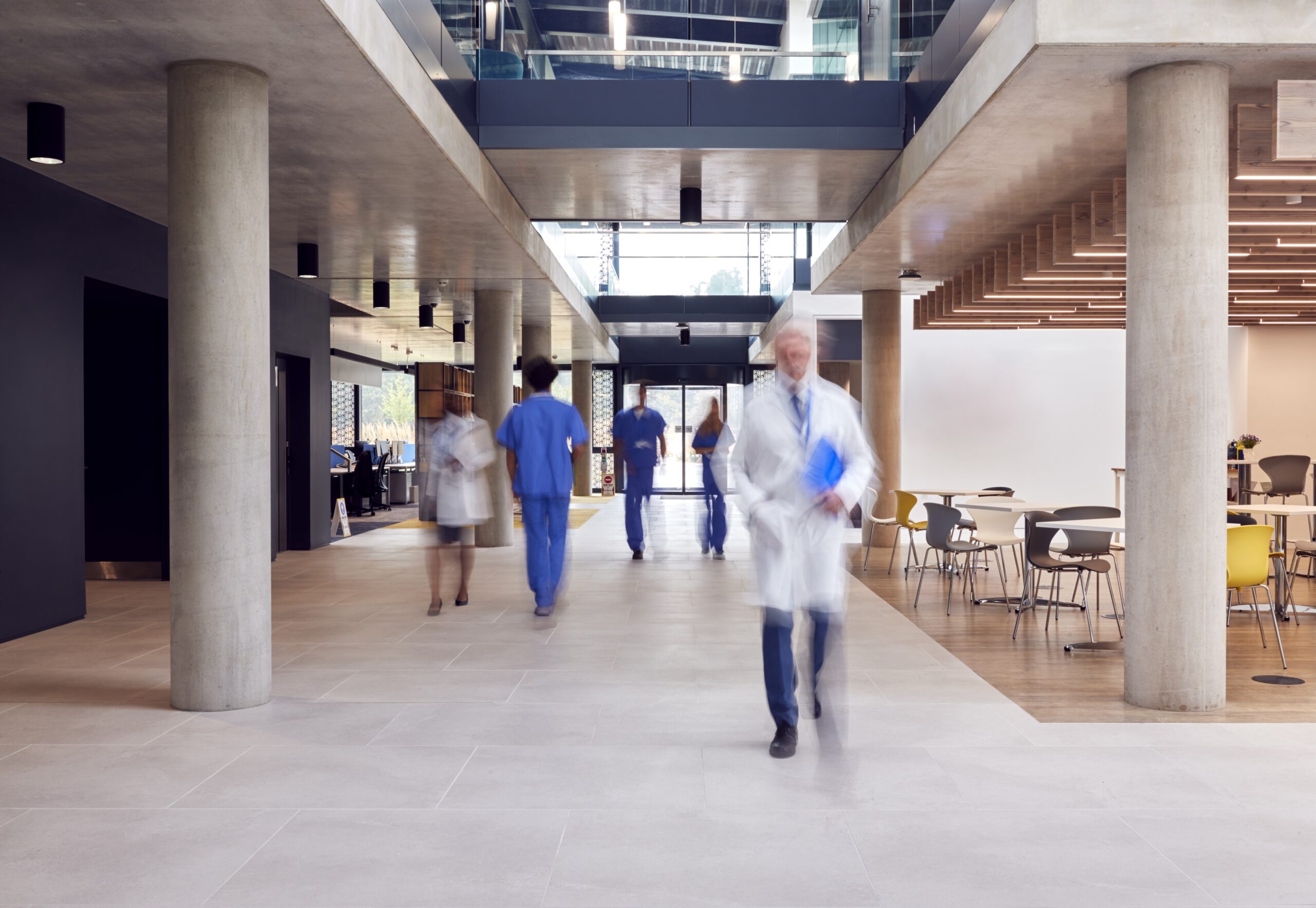 A hospital corridor with doctors, nurses, and patients walking throughout.